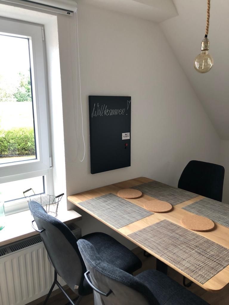 Eine Küche mit Tisch und Stühlen und einer Tafel an der Wand.