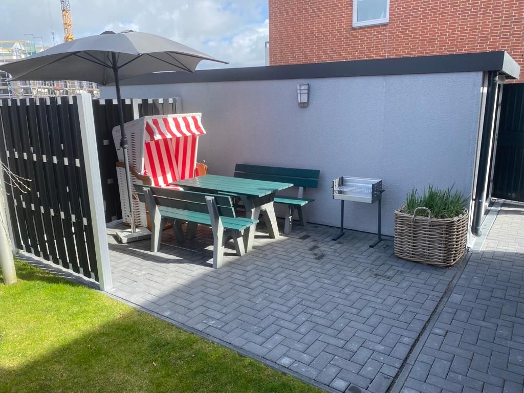 Eine Terrasse mit Tisch, Stühlen und Sonnenschirm.