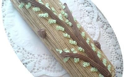 Ein Kuchen in Form eines Baumastes auf einem Teller.