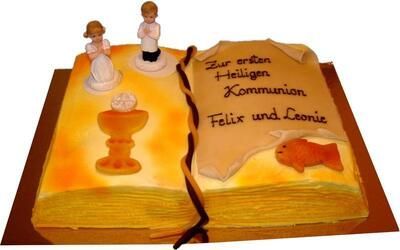 Ein Kuchen, der wie ein offenes Buch aussieht und auf dem die Worte „Zur ersten heiligen Kommunion“ stehen