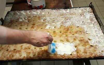 Eine Person bestreicht ein Stück Kuchen mit Sahne.