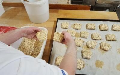 Eine Person backt Kekse auf einem Tablett auf einem Holztisch.