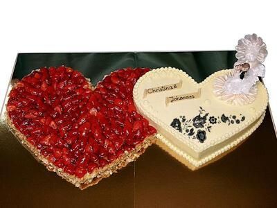 Auf einem Tisch stehen zwei herzförmige Kuchen mit Erdbeeren darauf.