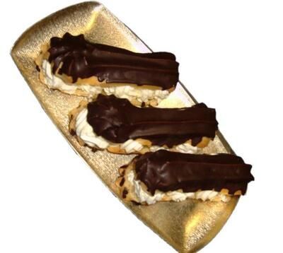 Drei Schokoladen-Eclairs auf einem goldenen Tablett auf weißem Hintergrund