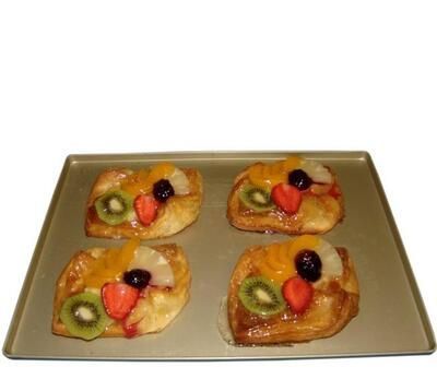 Auf einem Tablett liegen vier Gebäckstücke mit Früchten.