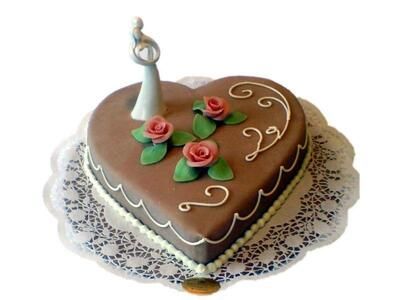 Ein herzförmiger Kuchen mit Rosen und einer Kerze obendrauf