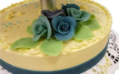 Ein Kuchen mit blauen Rosen und grünen Blättern darauf