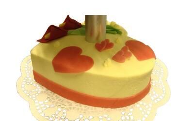 Ein gelber Kuchen mit roten Herzen und Blumen darauf