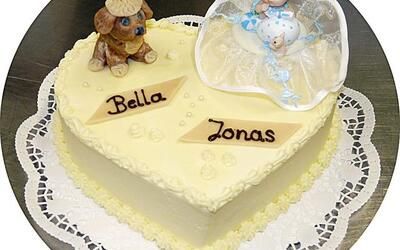 Ein herzförmiger Kuchen mit einem Hund und einem Baby obendrauf.