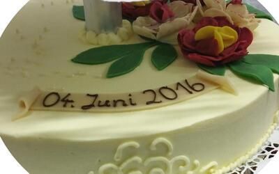 Ein weißer Kuchen mit Blumen und dem Datum 04. Juni 2016 darauf