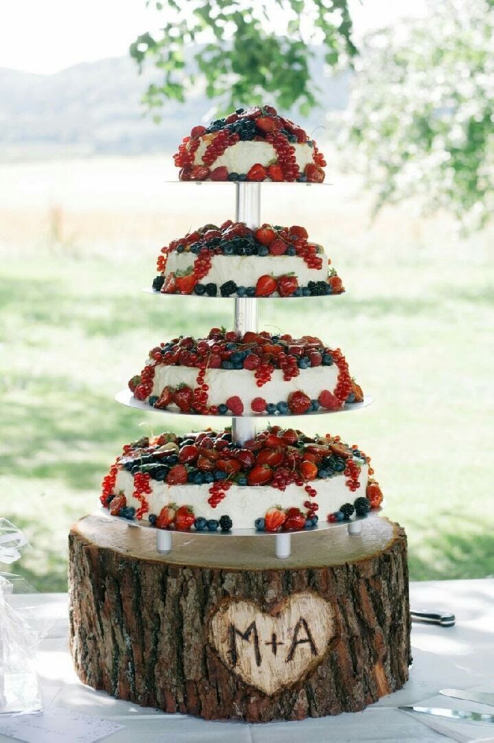 Eine Hochzeitstorte liegt auf einem Baumstumpf.