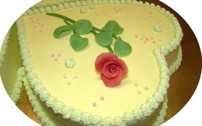 Ein herzförmiger Kuchen mit einer roten Rose obenauf