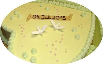 Ein gelber Kuchen mit zwei weißen Tauben und dem Datum 04. Juli 2015 darauf.