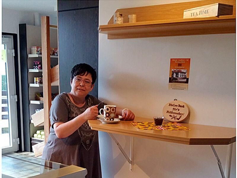 Eine Frau hält in einer Küche eine Tasse Kaffee.