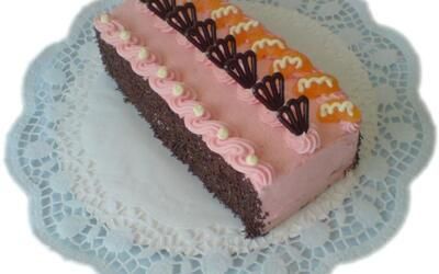 Ein Kuchen mit rosa Zuckerguss und Schokoladenherzen auf einem weißen Teller.