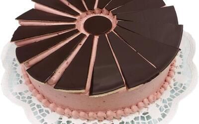 Auf einem weißen Teller liegt ein Schokoladenkuchen mit rosa Zuckerguss.