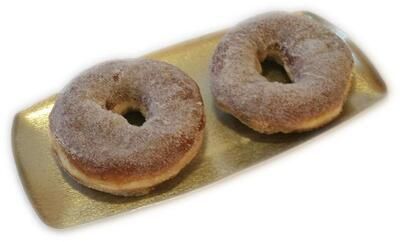 Zwei Donuts liegen auf einem goldenen Tablett auf weißem Hintergrund.