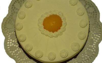 Auf einer weißen Spitzenserviette liegt ein weißer Kuchen mit gelber Mitte.