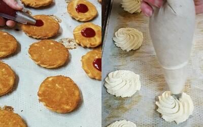 Eine Person versieht Kekse mit Zuckerguss und einem Spritzbeutel.