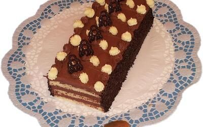 Auf einer Spitzenserviette liegt ein Schokoladenkuchen mit Tupfen.