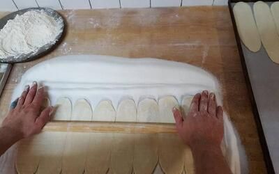 Eine Person schneidet auf einem Holztisch Formen aus Teig.