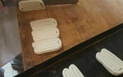 Eine Person schneidet ein Stück Teig auf einem Holztisch.