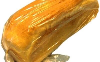 Auf einem Tisch liegt ein in Plastik eingewickelter Laib Brot.