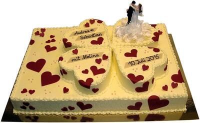 Eine Hochzeitstorte mit Herzen und einer Braut- und Bräutigamfigur obendrauf.