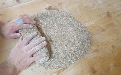 Eine Person knetet Teig auf einem Holztisch.