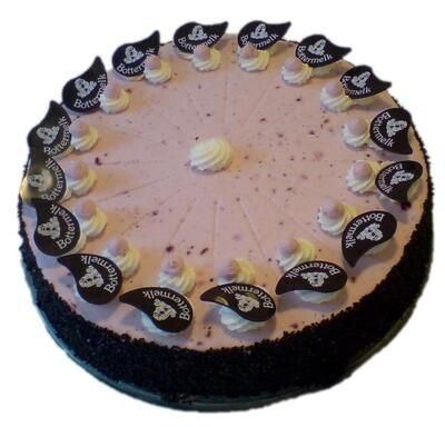 Ein rosa Kuchen mit schwarzem Zuckerguss und Schokoladenblättern mit der Aufschrift „Baumkuchen“