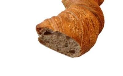 Eine Nahaufnahme eines Stücks Brot auf weißem Hintergrund.