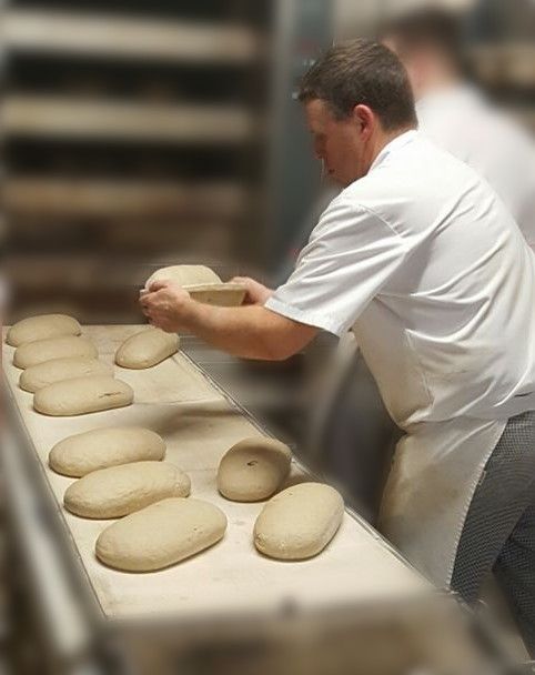 Ein Mann backt Brot auf einem Förderband