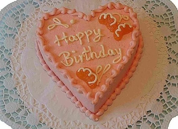 Ein rosa herzförmiger Kuchen mit der Aufschrift „Happy Birthday“