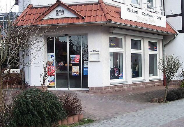 Ein weißes Gebäude mit einem roten Dach und einer Glasschiebetür