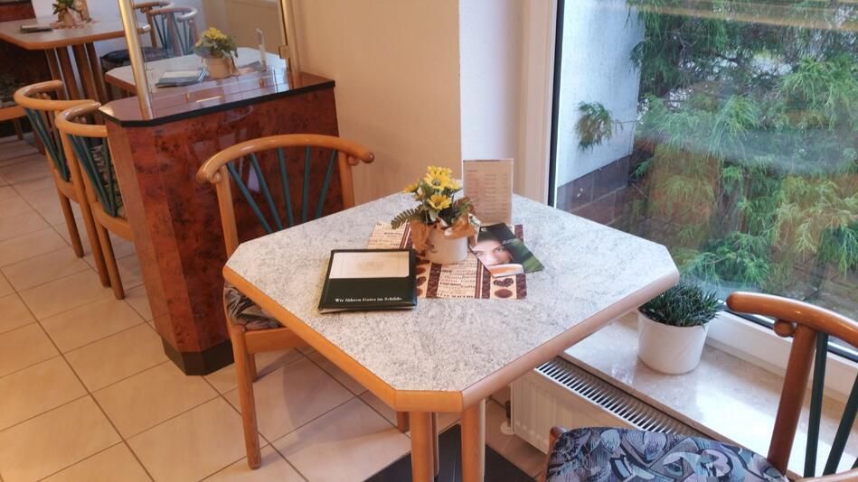 Ein kleiner Tisch und Stühle in einem Restaurant neben einem Fenster.