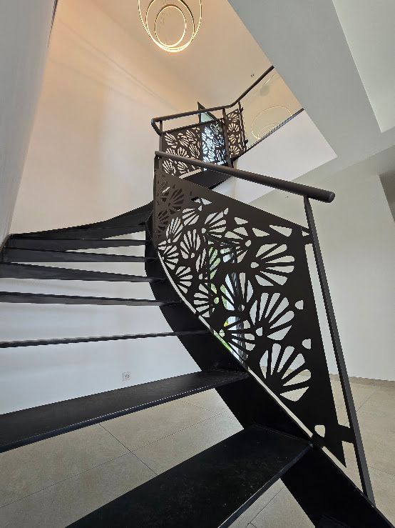 Escalier en colimaçon noir avec panneaux métalliques décoratifs.