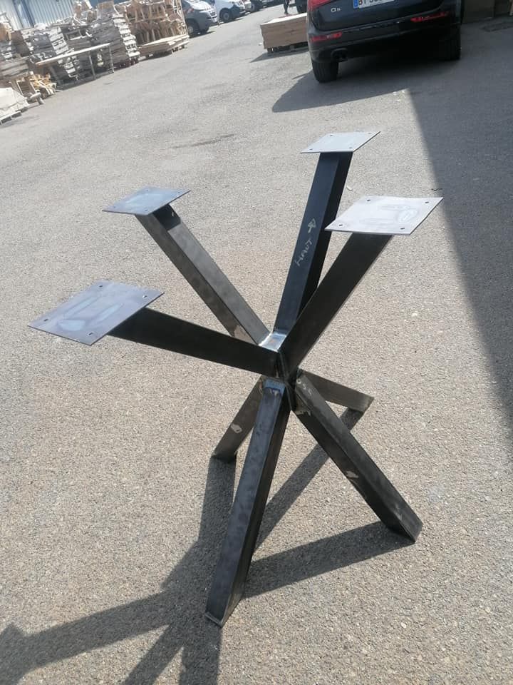 Base de table en métal avec quatre pieds inclinés et plaques supérieures, extérieur sur asphalte.