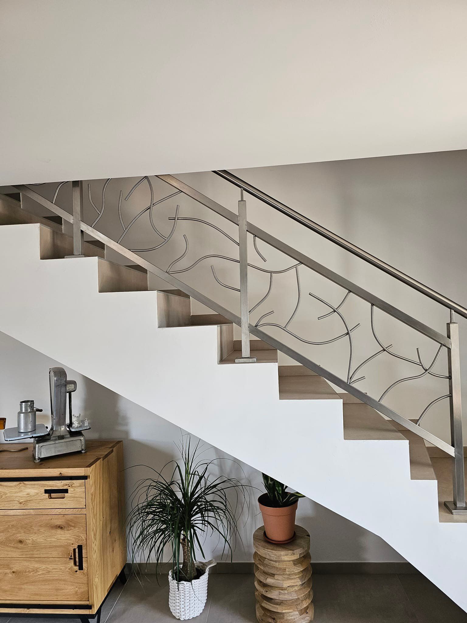 Escalier moderne avec rampe décorative en métal et marches en bois.