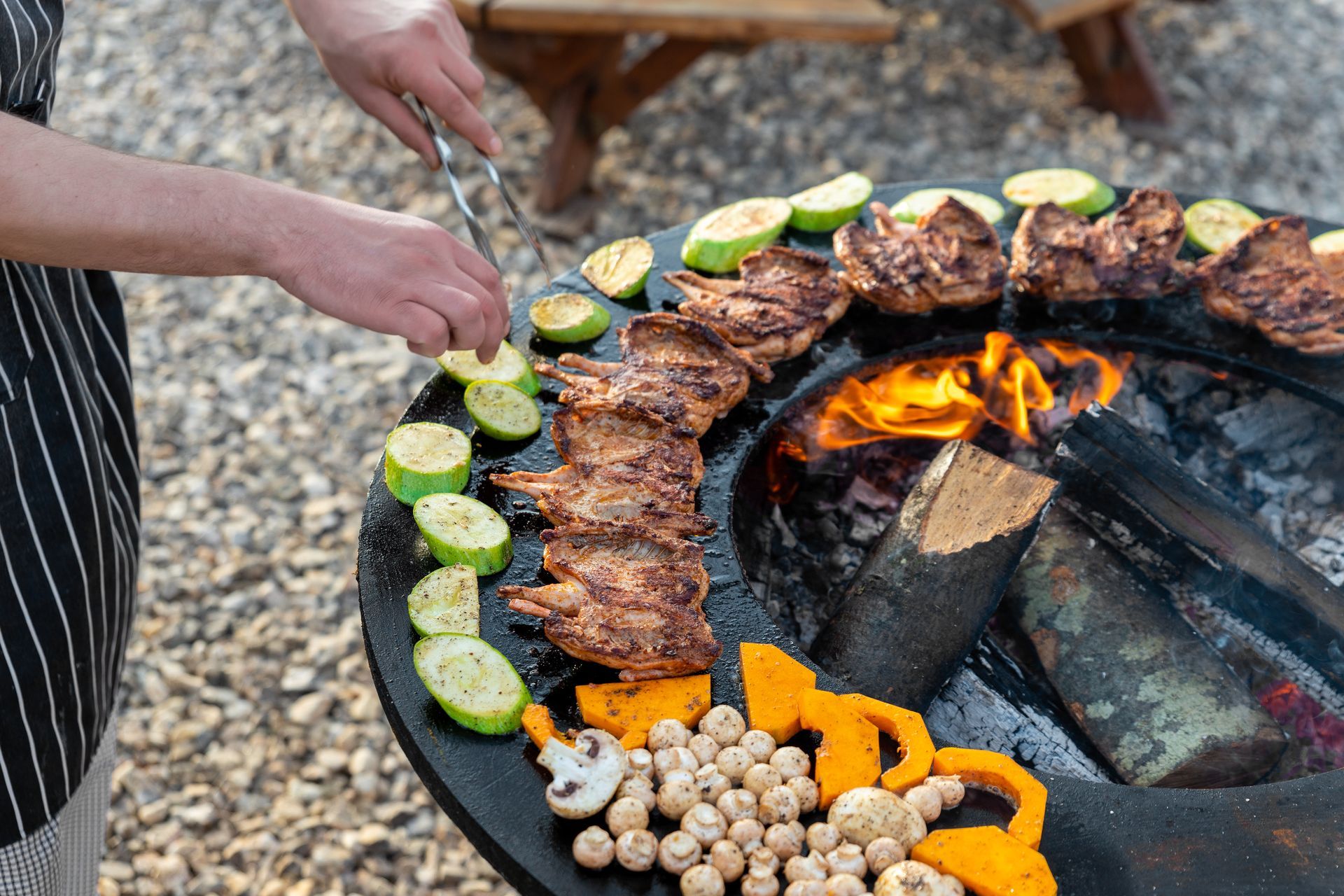 Personne faisant griller des légumes et de la viande sur un foyer de braséro.