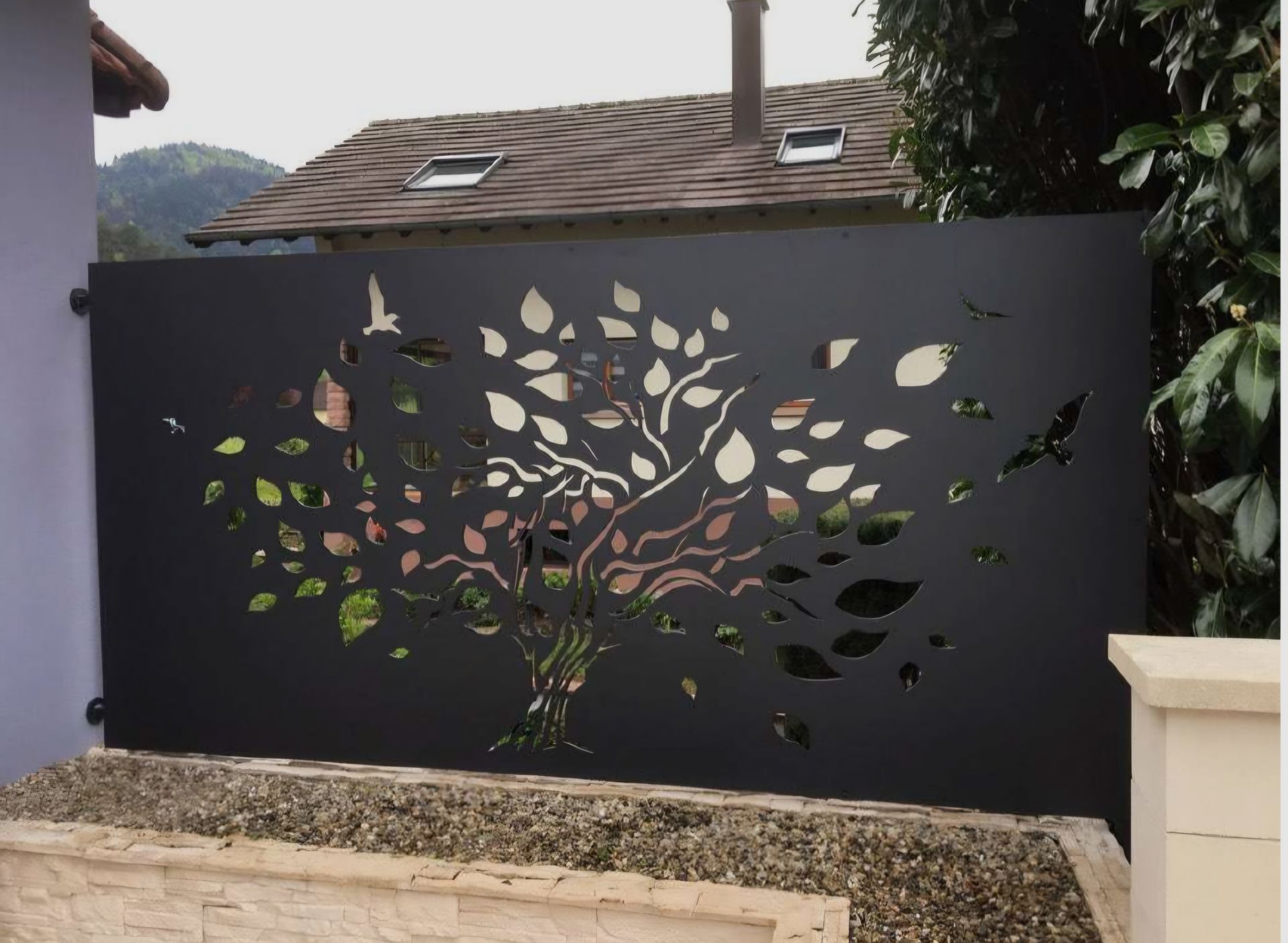 Portail en bois et métal noir sur une allée en béton avec toile de fond de montagne.
