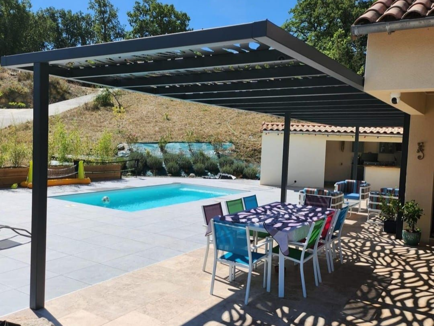 Des lattes en acier grises au plafond avec une fine bande de lumière, contre un ciel bleu avec des nuages.