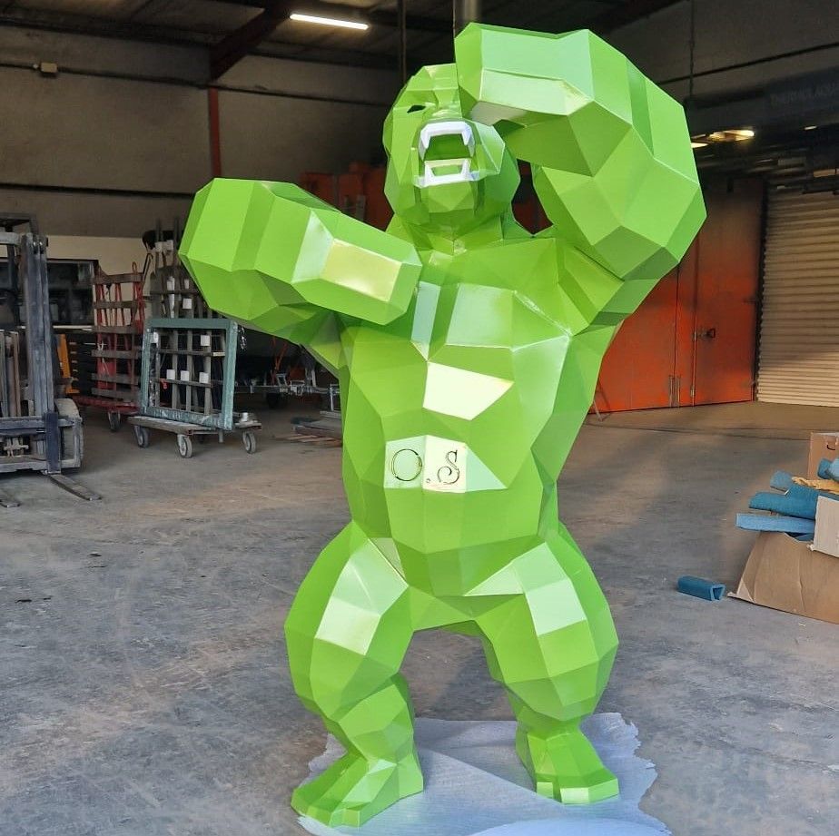 Statue de gorille polygonale verte avec les bras levés, à l'intérieur.