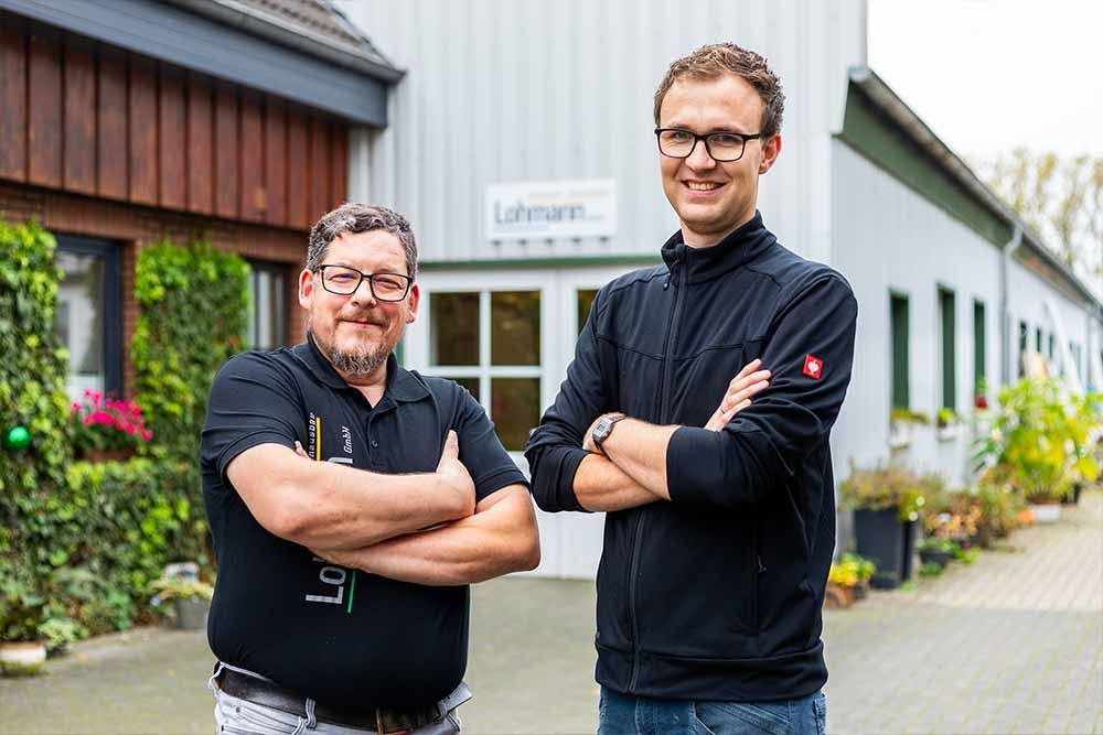 zwei Männer stehen mit verschränkten Armen vor einem Gebäude .