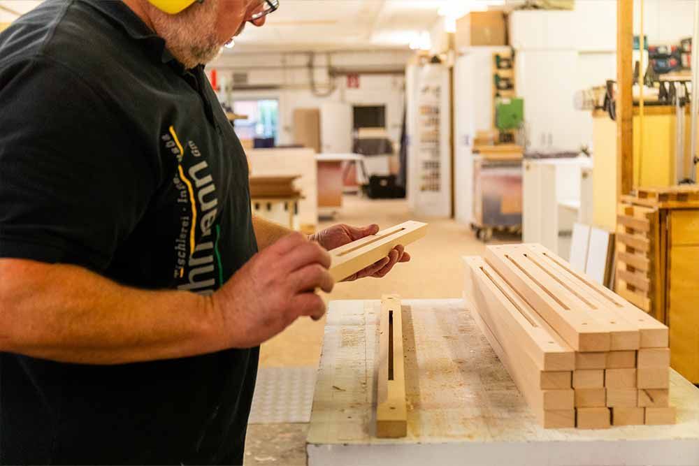 ein mann arbeitet an einem stück holz und trägt ein t-shirt mit der schrift millmann