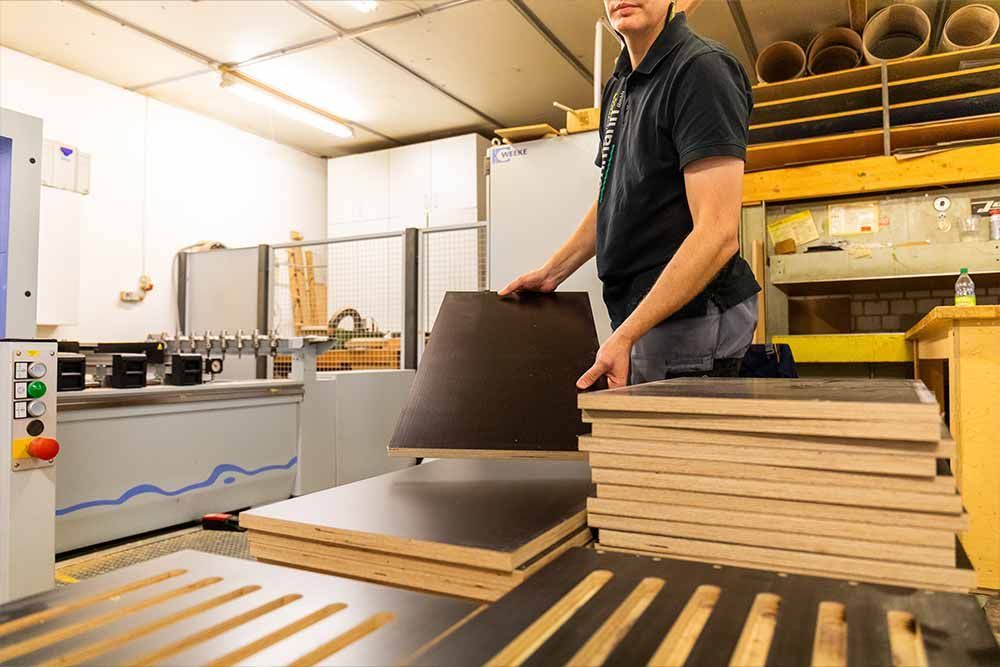 ein mann hält ein stück holz in einer fabrik