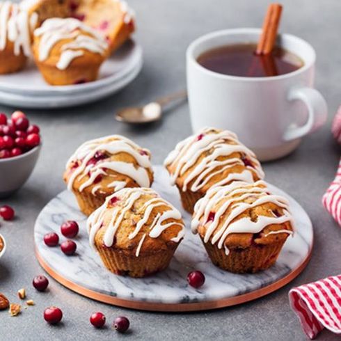 Una tabla de cortar de mármol cubierta con muffins y una taza de té.