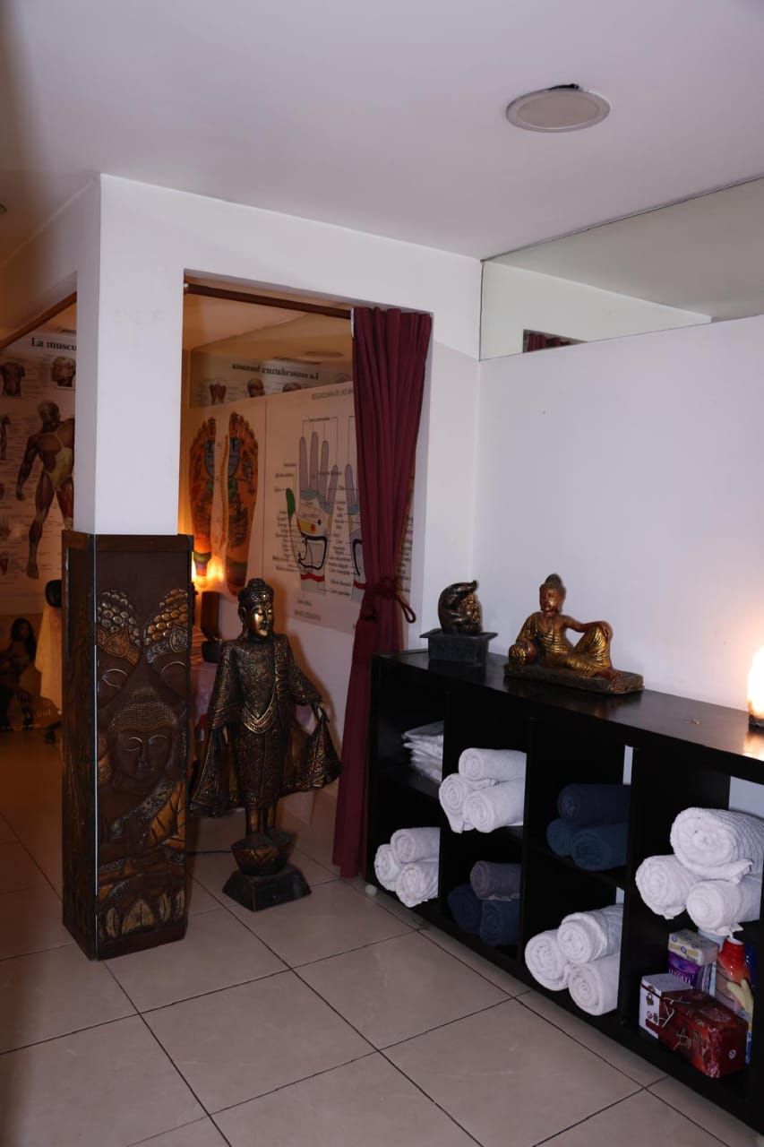 Pequeña zona de santuario con estatuas de Buda, velas y estantes en una habitación interior alicatada.