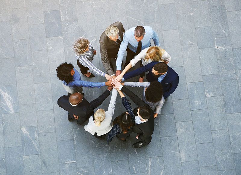 Eine Gruppe von Leuten legt ihre Hände zu einem Kreis zusammen.