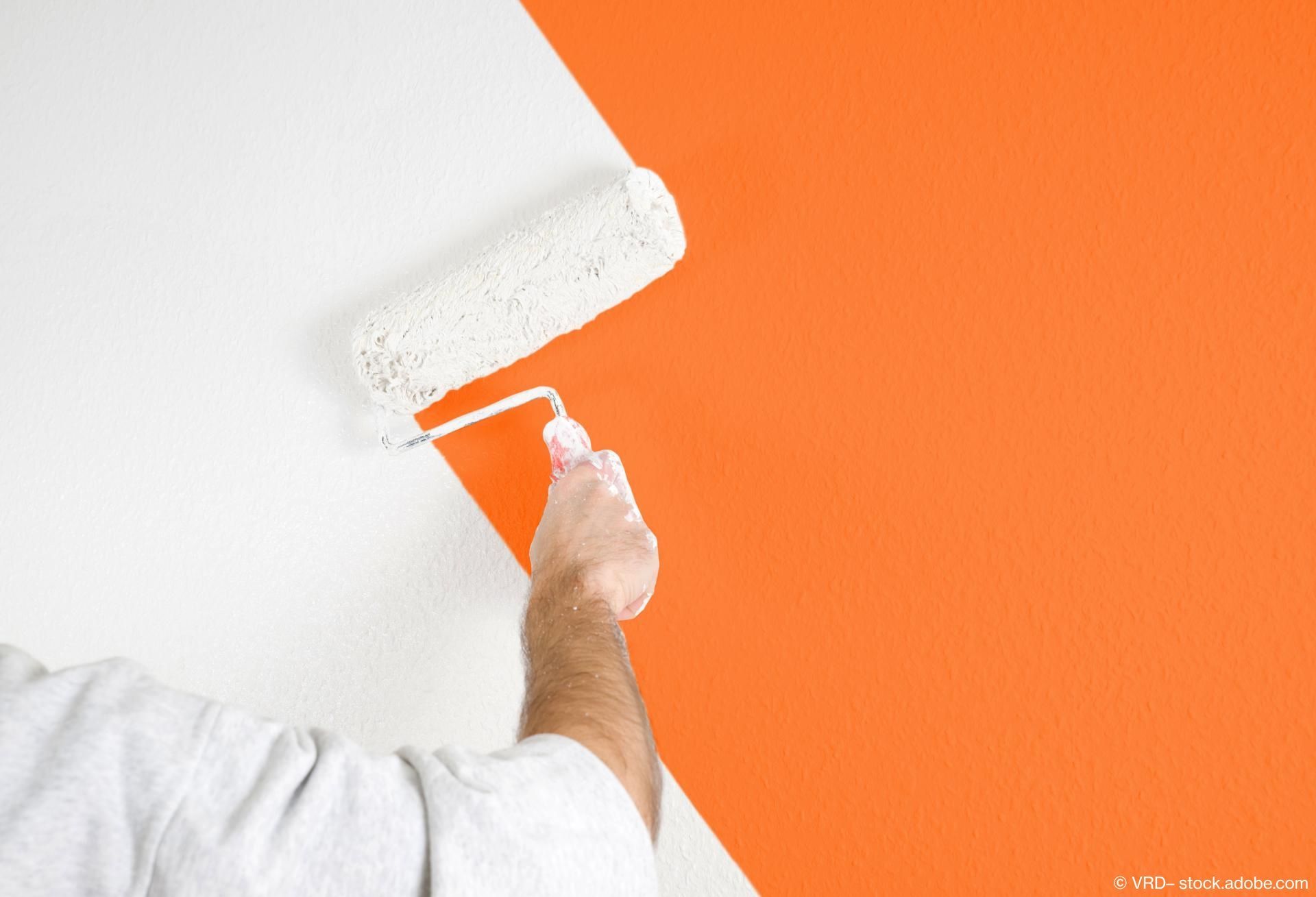 Orangefarbene Wand wird mit Weiße Farbe gestrichen