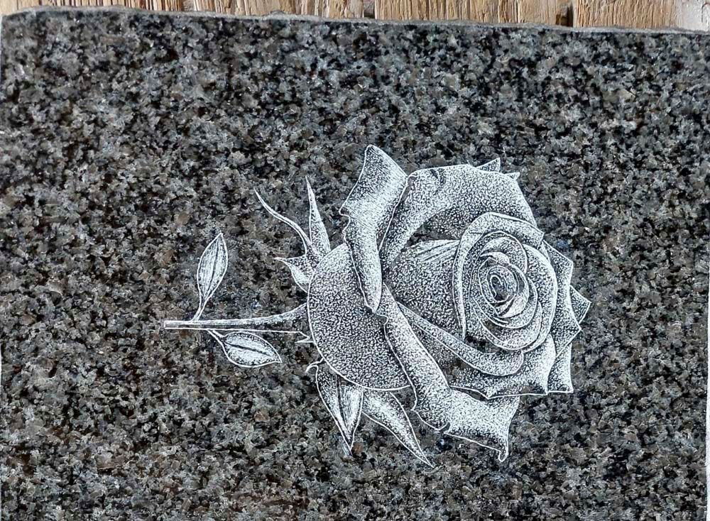 Eine schwarz-weiße Zeichnung einer Rose auf einer Granitplatte.
